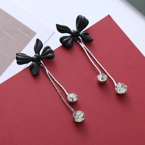 Détail de boucles d'oreilles franges avec nœud noir mat et gouttes de cristal brillant