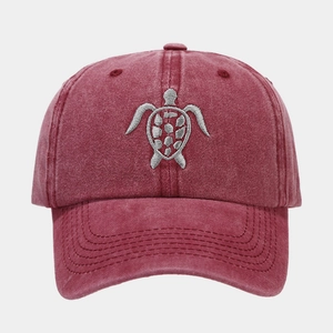 Close-up of vintage washed burgundy baseball cap featuring detailed sea turtle embroidery
