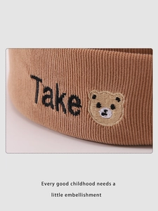 Gros plan du bonnet en tricot marron pour bébé avec broderie Take et motif d'ours