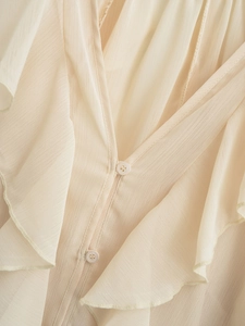 Detailed view of apricot blouse with ruffled layers and matching buttons texture