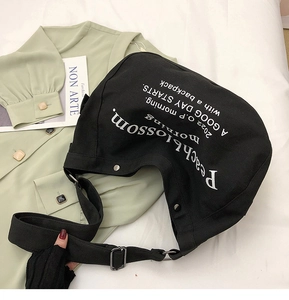 Détail du grand sac messager en toile noire avec imprimé typographique artistique