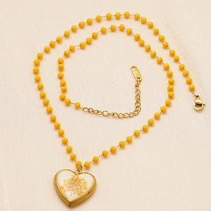 Detail of 18K gold plated heart locket pendant with dried flowers and yellow beads