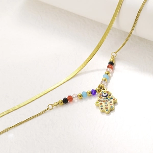 Detail of gold-plated double-layer necklace with Hamsa hand and evil eye charms