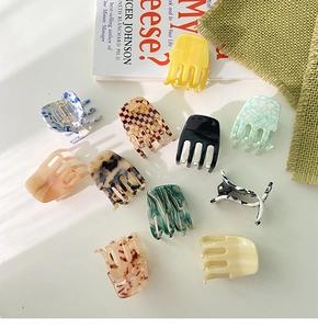 Detailed flat lay of small acetate hair claws in various patterns like marble and cow print