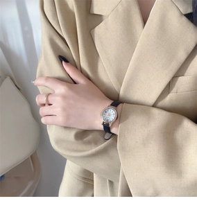 Detail of luxury ladies watch with shell dial, gold bezel and black leather strap