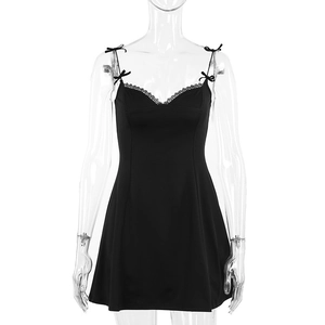 Détail d'une mini robe noire ajustée avec des nœuds aux épaules et des bords en dentelle