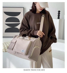Detail view of large beige travel bag with multiple pockets and adjustable shoulder strap