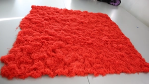 Macro detail of thick bright red artificial moss turf with realistic fiber texture