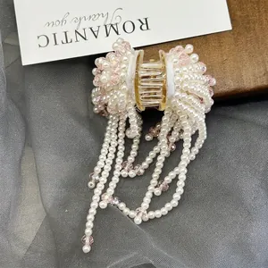 Elegant pearl and pink crystal fringe hair claw clip with golden metal base on mesh