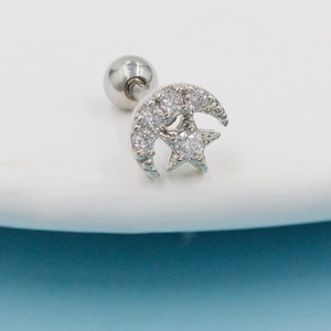 Macro view of stainless steel moon and star stud piercing with clear cubic zirconia stones
