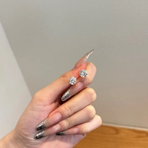 Close-up of sparkling round zircon stud earrings in gold claws held by hand
