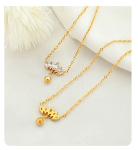 Detailed close-up of 18K gold-plated crown pendant necklaces on soft white fabric