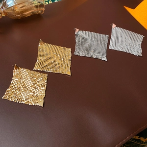 Detail of geometric triangle drop earrings in gold and silver mesh texture