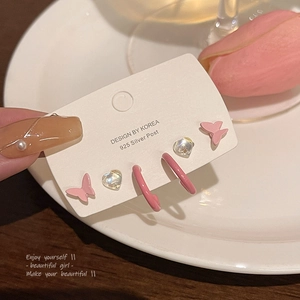 Detalle de pendientes de mariposa y corazón rosa en tarjeta con poste de plata 925