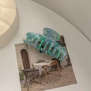 Detail shot of a large marble patterned hair claw clip on a minimalist white table