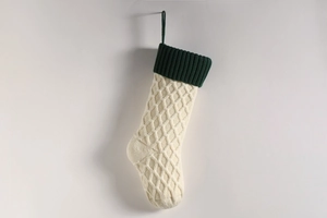 Nahaufnahme von cremefarbenem Weihnachtsstrumpf mit grünem Rand und Rautenmuster
