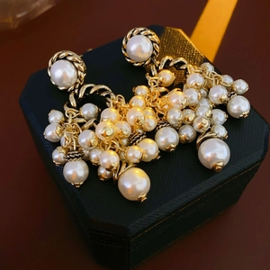 Macro shot of vintage gold chain links and white stacked pearls on elegant drop earrings