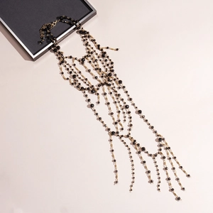 Detail of layered black beaded chest chain with golden metallic fringe links