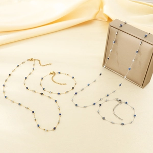 Detail of gold and silver four-leaf clover jewelry sets with blue beads on silk fabric