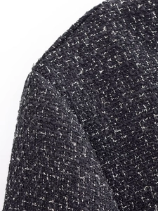 Close-up of black and white tweed jacket shoulder showing detailed fabric weave and texture