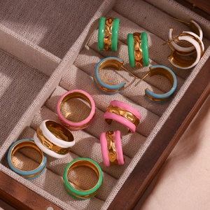 Close-up of 18K gold plated ripple rings and earrings with colorful enamel in a wooden box