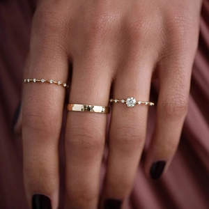 Close-up of stacked luxury gold rings with micro-pave diamonds on red silk fabric