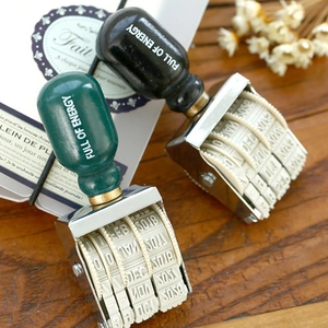 Vintage roller date stamp with wooden handle and metal frame on a rustic wood background