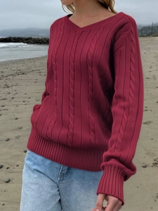 Women's V-neck wine red cable knit sweater styled with light jeans on a beach setting