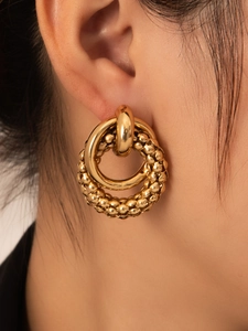 Close-up of golden double hoop earrings with polished inner and beaded texture outer rings