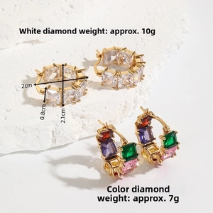 Detail view of chunky gold hoop earrings with white and colorful square-cut zircons