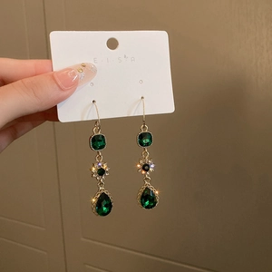 Detail of emerald drop earrings with gold floral zircon accents and starry sparkle