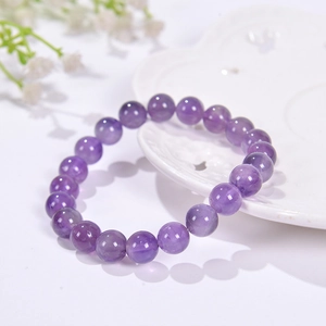 Macro view of 8mm purple natural stone beads on an elastic bracelet on a white table