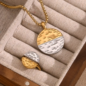 Detail of hammer-textured gold and silver two-tone necklace and ring set in jewelry box