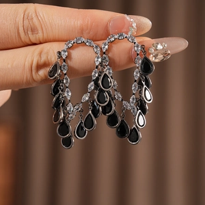 Detailed view of silver needle drop tassel earrings with black stones and sparkling zircons