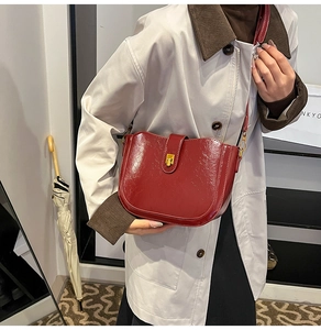 Detail of burgundy saddle bag with glossy oil wax leather and gold buckle clasp
