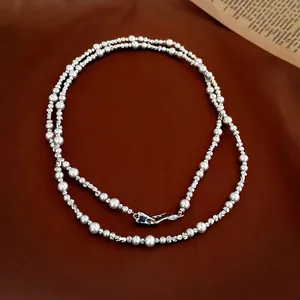 French style double-layer pearl and silver bead necklace on brown leather background