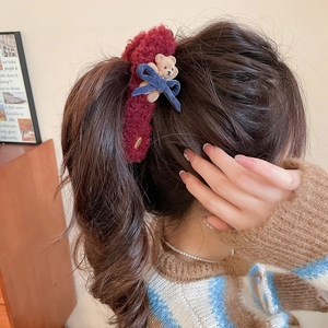 Detail of burgundy plush hair clip with a brown bear and blue velvet bow on ponytail