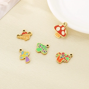 Colorful mushroom pendants in gold stainless steel scattered on beige linen background