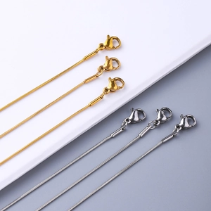 Detail of gold and silver snake bone chains with lobster clasps on a clean background