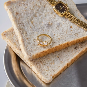 Creative display of a gold zircon ring and watch placed on whole wheat bread