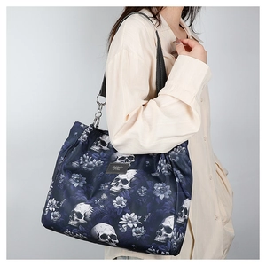 Detail of navy tote bag with skull and floral patterns featuring a silver chain strap