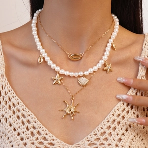 Detail of layered gold necklace with shell and starfish charms on a model