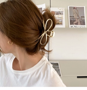 Detail view of large gold bow hair claw clip styled on a woman's hair in an elegant updo