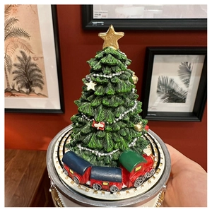 Close-up of a green vintage Christmas tree music box with a rotating toy train base