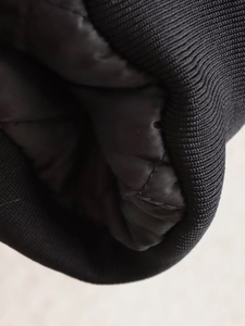 Détail des poignets en tricot côtelé et doublure matelassée sur veste bomber noire