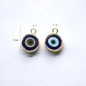 Detailed view of evil eye enamel charms in blue and gold for DIY jewelry making