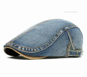 Detail of medium blue washed denim flat cap with orange contrast stitching and metal buckle