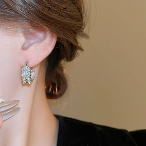 Close-up of silver U-shaped hoop earrings with marquise-cut zircons in wheat leaf design