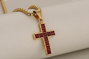 Detailed close-up of golden stainless steel cross pendant with red gemstones