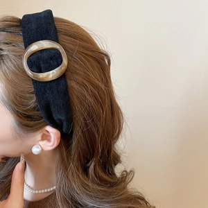 Primo piano della fascia nera in tessuto con anello in resina ambrata sulla modella